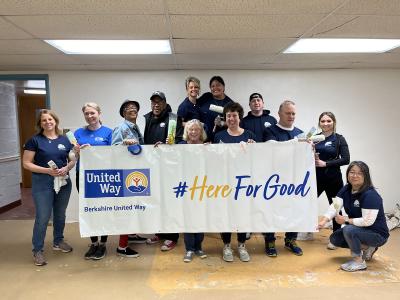 group of people holding a sign in front of a painted white wall